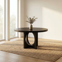 Loyal Round 6 Seater Dining Table styled in a modern dining room with black chairs, greenery, pendant lighting, and neutral decor.