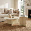 Aidan Cross Legs End Table pair styled near a fireplace with books and minimalist decor on the round tabletops.