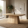Langston Dining Table in natural wood finish styled in a warm modern dining room with a textured rug, decorative vase, and indoor olive tree.