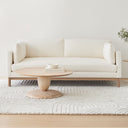Leandro round natural wood coffee table styled in a minimalist living room with a cream sofa