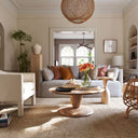 Leandro round natural wood coffee table styled in a warm transitional living room with a grey sofa