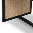 Angled close-up of the Dennis Woven Dining Table highlighting the textured cane insert and black tabletop corner.